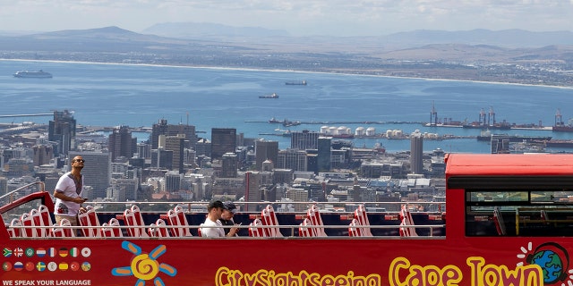 An open-air double-decker sightseeing bus stops on the slopes of Table Mountain, overlooking the city of Cape Town, South Africa, Friday, March 20, 2020 (AP Photo)