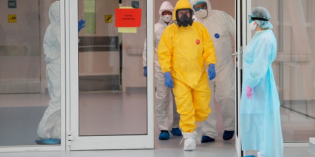 Russian President Vladimir Putin, center right, wearing a protective suit enters a hall during his visit to the hospital for coronavirus patients in Kommunarka settlement, outside Moscow, Russia, Tuesday, March 24, 2020.