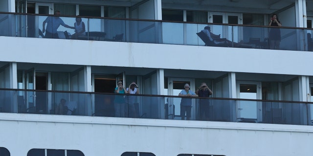 Passengers look out from the Zaandam cruise ship, anchored in the bay of Panama City. (AP Photo/Arnulfo Franco)