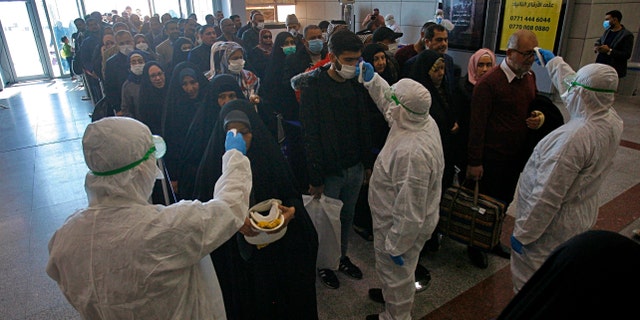 Friday, Feb. 21, 2020: Medical staff check passengers arriving from Iran in the airport in Najaf, Iraq. Coronavirus-infected travelers from Iran already have been discovered in Lebanon and Canada.