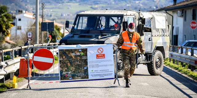 An Italian army soldier blocks off a road leading to the village of Vo'Euganeo, in Italy's northern Veneto region, on Friday, Feb. 28, 2020. Vo'Euganeo is the epicenter of the Veneto cluster of the new virus. (Claudio Fulan/LaPresse via AP)