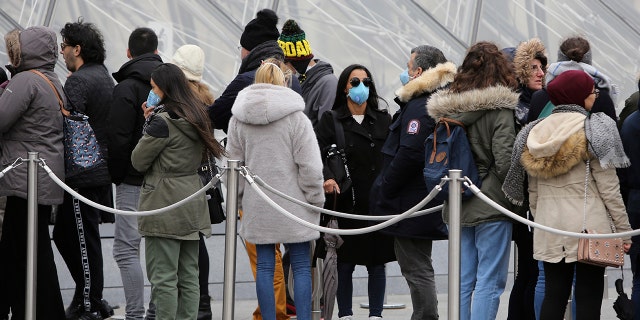 Tourists, some wearing a mask, queue to enter the Louvre museum Friday, Feb. 28, 2020 in Paris. The world is scrambling to get on top of the new coronavirus outbreak that has spread from its epicenter in China to most corners of the planet. (AP Photo/Rafael Yaghobzadeh)