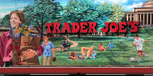 FILE - In this Aug. 13, 2019, file photo, Trader Joe's logo hangs on a mural at it's market in Cambridge, Mass.. The man who created Trader Joe's markets with a vision that college-educated but poorly paid young people would buy healthy foods if they could only afford them has died. Joe Coulombe's family says he died Friday at age 89. (AP Photo/Charles Krupa)