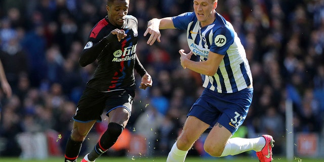 Brighton and Hove Albion's Dan Burn, right, and Crystal Palace's Wilfried Zaha in action during their English Premier League soccer match at the AMEX Stadium in Brighton, England, Saturday Feb. 29, 2020. (Gareth Fuller/PA via AP)