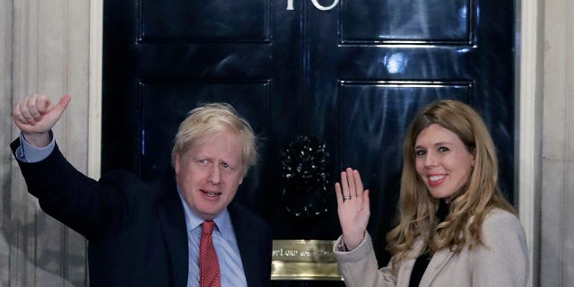 Britain's Prime Minister Boris Johnson and his partner Carrie Symonds wave from the steps of number 10 Downing Street in London, in December 2019. (Associated Press)