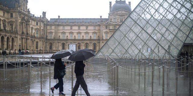 People walk by the Louvre museum, in Paris, France.(AP Photo/Rafael Yaghobzadeh)