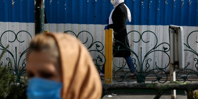 Pedestrians wearing face masks walk on the sidewalks in northern Tehran, Iran, Sunday, March 1, 2020. While the new coronavirus has extended its reach across the world, geographic clusters of infections were emerging, with Iran, Italy and South Korea seeing rising cases. (AP Photo/Vahid Salemi)