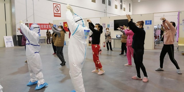 In this Feb. 18, 2020, photo released by Zhang Junjian, medical workers lead patients in exercises at the Wuhan Living Room Temporary hospital in Wuhan in central China's Hubei province.