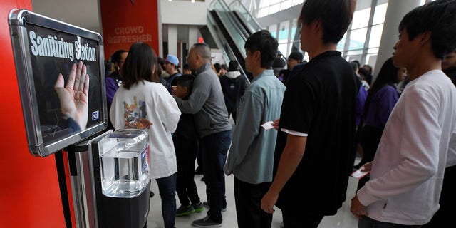 Fans walk by a sanitizing station at Staples Center prior to an NBA basketball game between the Los Angeles Clippers and the Philadelphia 76ers Sunday, March 1, 2020, in Los Angeles. (AP Photo/Mark J. Terrill)