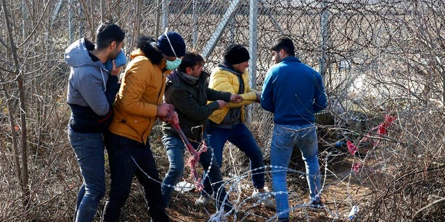 Migrants try to cut the fence at the Turkish-Greek border near the Pazarkule border gate in Edirne, Turkey on Monday, March 2, 2020. (AP Photo/Darko Bandic)