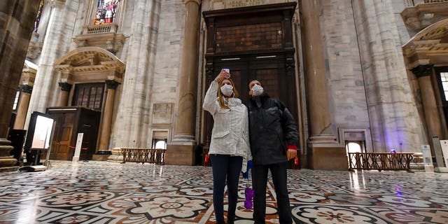 Tourits wearing face masks take pictures inside the Duomo gothic cathedral as it reopened to the public after being closed due to the COVID-19 virus outbreak in northern Italy, in Milan, Monday, March 2, 2020.