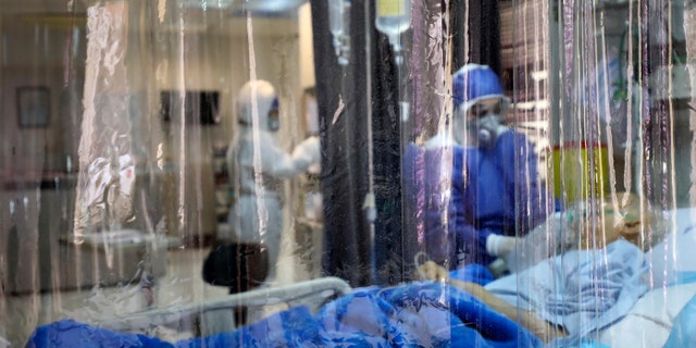 In this Sunday, March 1, 2020 photo, a medic treats a patient infected with coronavirus, at a hospital in Tehran, Iran.  (Koosha Mahshid Falahi/Mizan News Agency via AP)