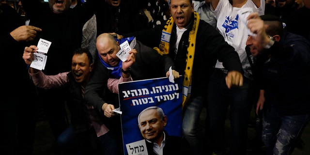 Israeli Prime Minister Benjamin Netanyahu's supporters celebrate first exit poll results for the Israeli elections at his party's headquarters in Tel Aviv, Israel, Monday, Feb. 2, 2020. (AP Photo/Ariel Schalit)
