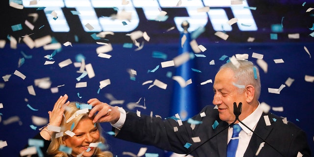 Israeli Prime Minister Benjamin Netanyahu, accompanied by his wife Sara, addresses his supporters after first exit poll results for the Israeli elections at his party's headquarters in Tel Aviv, Israel, Monday, Feb. 2, 2020. (AP Photo/Ariel Schalit)