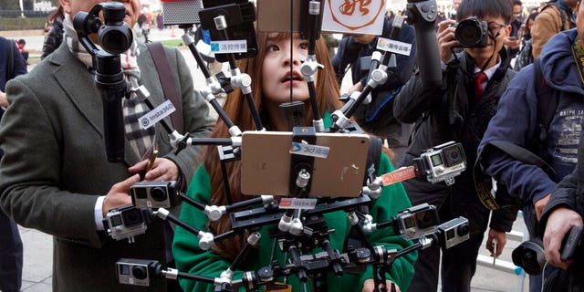 FILE: A Chinese journalist operates a harness with multiple recording devices capable of recording and multiple live streamings outside the Great Hall of the People where the opening session of the Chinese People's Political Consultative Conference (CPPCC) was held in Beijing, China.