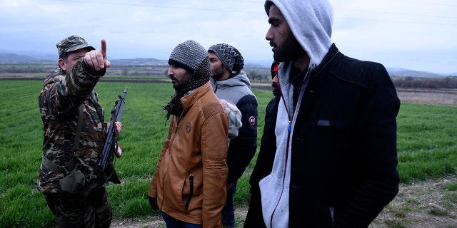 A Greek army officer detains migrants in the village of Ardanio at the Greek-Turkish border on Wednesday, March 4, 2020. (AP Photo/Giannis Papanikos)