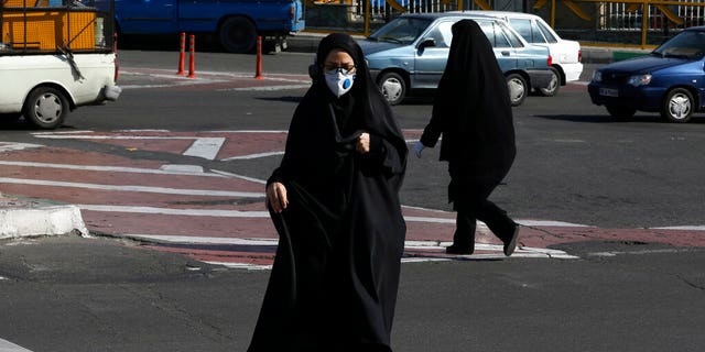 A woman wearing a face mask crosses an intersection in northern Tehran, Iran, Wednesday, March 4, 2020. With deaths spiking in Iran and Italy and infections spreading quickly through Europe, the Mideast and the Americas, countries were considering new drastic measures to curb the new coronavirus that first emerged in China.
