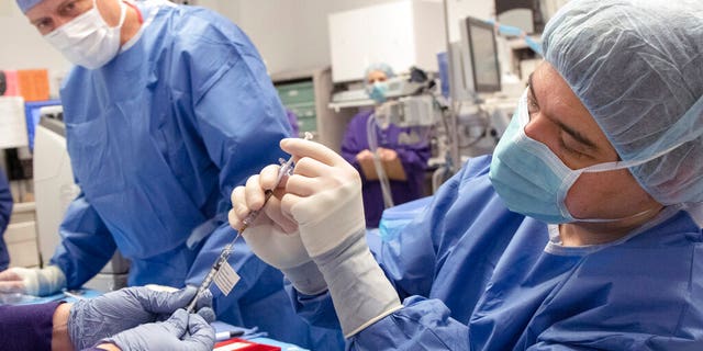 Dr. Andreas Lauer, right, prepares to perform the first-ever in vivo CRISPR gene edit procedure for the BRILLIANCE clinical trial at the school's Casey Eye Institute in Portland, on a patient who had an inherited form of blindness. I
