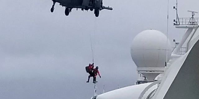In this photo provided by Michele Smith, a National Guard helicopter delivering virus testing kits lowers crew down to the Grand Princess cruise ship Thursday, March 5, 2020, off the California coast.