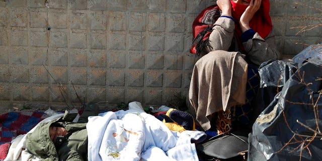 A migrant woman sits as a baby sleeps at an abandoned building in Edirne, near the Turkish-Greek border on Friday, March 6, 2020. 