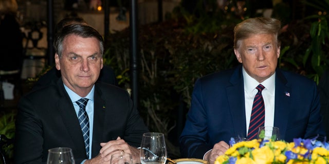 President Donald Trump is seated before a dinner with Brazilian President Jair Bolsonaro, left, at Mar-a-Lago, Saturday, March 7, 2020, in Palm Beach, Fla. (AP Photo/Alex Brandon)