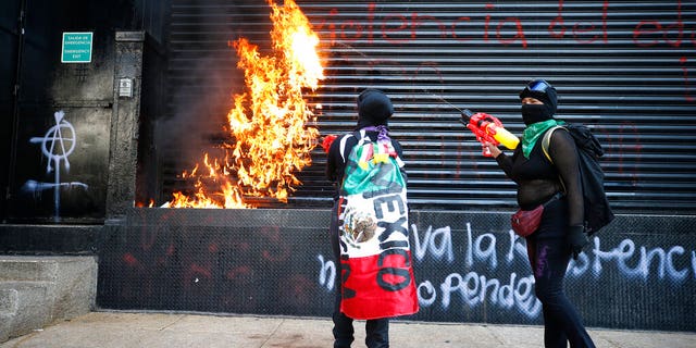 Demonstrators set fire to the entrance of a building during a march for International Women's Day in Mexico City, Sunday, March 8, 2020.