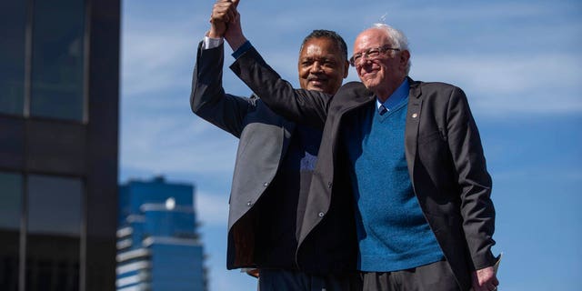 Sen. Bernie Sanders and Rev. Jesse Jackson wave to the crowd at a rally for Sanders at Calder Plaza in Grand Rapids, Michigan on Sunday, March 8, 2020. Michigan's presidential primary is Tuesday. (Anntaninna Biondo/The Grand Rapids Press via AP)