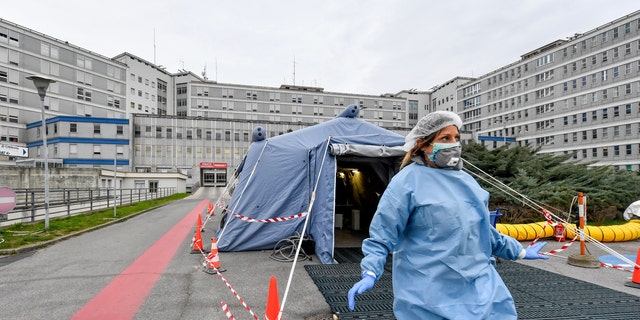 FILE - In this Feb. 29, 2020 file photo, a paramedic walks out of a tent that was set up in front of the emergency ward of the Cremona hospital, northern Italy. Italian doctors celebrated one small victory in their battle against the coronavirus Monday after Patient No. 1, a 38-year-old named Mattia was moved out of intensive care. (Claudio Furlan/Lapresse via AP, file)