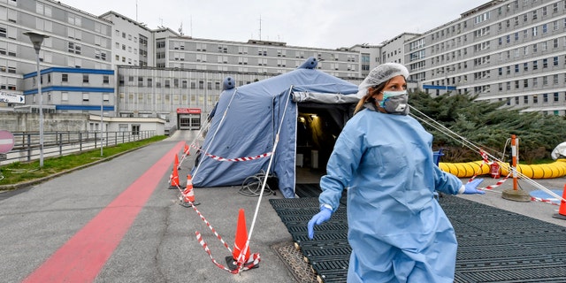 FILE - In this Feb. 29, 2020 file photo, a paramedic walks out of a tent that was set up in front of the emergency ward of the Cremona hospital, northern Italy. Italian doctors celebrated one small victory in their battle against the coronavirus Monday after Patient No. 1, a 38-year-old named Mattia was moved out of intensive care. (Claudio Furlan/Lapresse via AP, file)