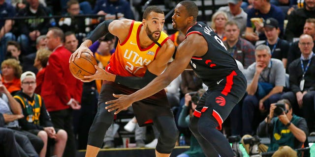Toronto Raptors center Serge Ibaka (9) guards against Utah Jazz center Rudy Gobert (27) in the first half during an NBA basketball game Monday, March 9, 2020, in Salt Lake City. 