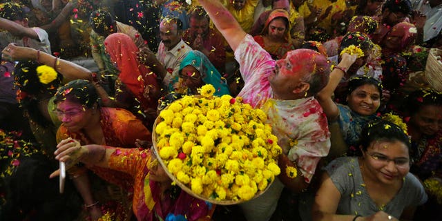 An Indian man throws flowers out to devotees during Holi festival celebration at the Lord Jagannath temple in Ahmedabad, India, Tuesday, March 10, 2020.