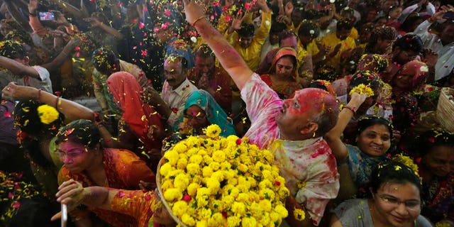 An Indian man throws flowers out to devotees during Holi festival celebration at the Lord Jagannath temple in Ahmedabad, India, Tuesday, March 10, 2020.