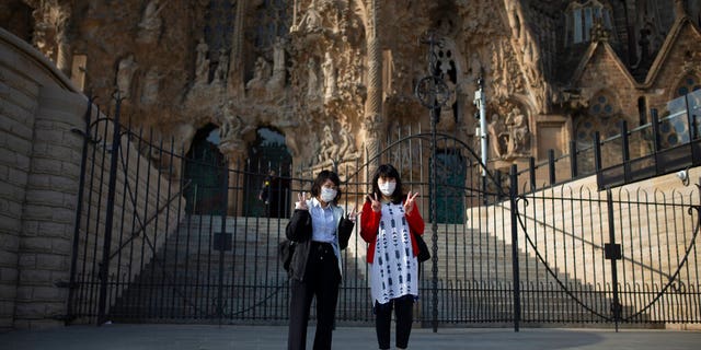 Tourists pose for a photo outside the Sagrada Familia basilica in Barcelona, Spain, Friday, March 13, 2020. The basilica closed its doors to visitors and suspend construction from Friday March 13 to prevent the spread of the new COVID-19 coronavirus. Spain, along with Italy and France, is among the countries worst hit by the virus so far in Europe.