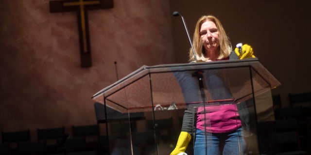 Linda Abott cleans the podium of Westmeade Baptist Church in Decatur, Ala., on Friday, March 13, 2020, in preparation of Sunday service. (Dan Busey/The Decatur Daily via AP)