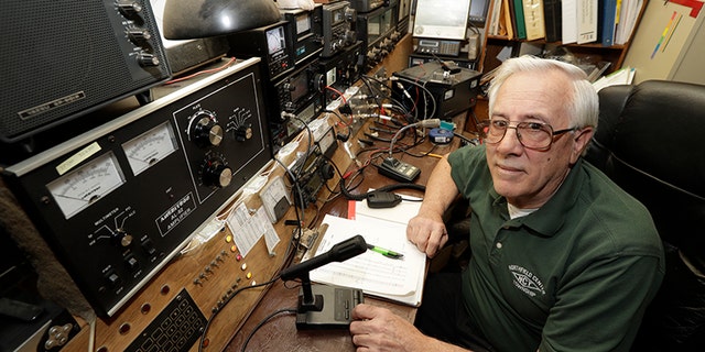 In this Friday, March 13, 2020 photo, Paul Buescher poses by his ham radio, in Northfield Center Township, Ohio. Buescher is one of 32 members of a group in northeastern Ohio that shares a farm packed with enough canned and dehydrated food and water to last for years. (AP Photo/Tony Dejak)