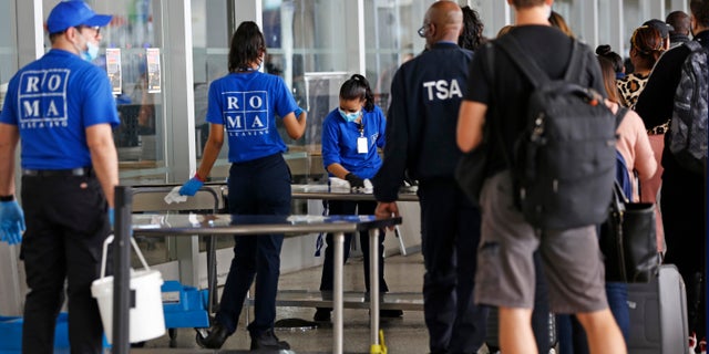 Cleaning crews scrub tables at a Transportation Security Administration checkpoint on March 14 at John F. Kennedy International Airport in New York. (AP Photo/Kathy Willens)