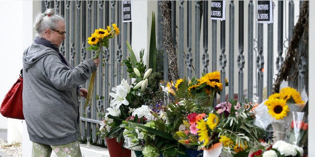 A woman prepares tp lay flowers outside the Al Noor mosque in Christchurch, New Zealand, Sunday, March 15, 2020. A national memorial in New Zealand to commemorate the 51 people who were killed when a gunman attacked two mosques one year ago has been canceled due to fears over the new coronavirus. (AP Photo/Mark Baker)