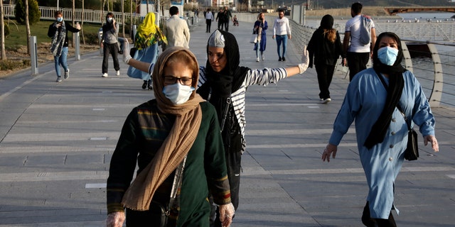People wearing face masks exercise on the shore of an artificial lake, in Western Tehran, Iran, Sunday, March 15, 2020. Many people in Tehran shrugged off warnings over the new coronavirus as authorities complained that most people in the capital are not treating the crisis seriously enough. For most people, the new coronavirus causes only mild or moderate symptoms. For some it can cause more severe illness. (AP Photo/Vahid Salemi)