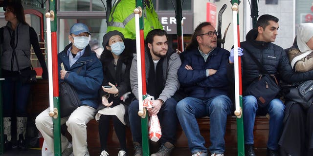 A man and woman wear masks while riding a Cable Car in San Francisco.