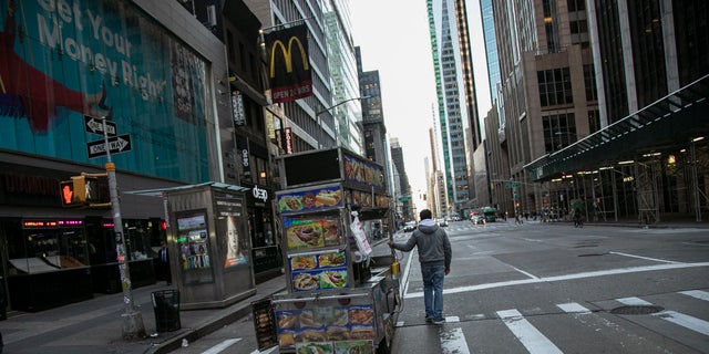 A food truck vendor pushes his cart down an empty street near Times Square in New York, on Sunday, March 15, 2020. (AP Photo/Wong Maye-E)