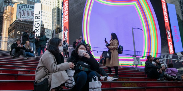 Japanese tourists wear face masks as they sit and chat in Times Square in New York, on Sunday, March 15, 2020. President Donald Trump on Sunday called on Americans to cease hoarding groceries and other supplies, while one of the nation's most senior public health officials called on the nation to act with more urgency to safeguard their health as the coronavirus outbreak continued to spread across the United States. (AP Photo/Wong Maye-E)