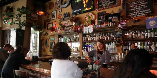 Bartender Lyndsay Przybyl, center rear, pours drinks for customers at Lush Lounge in San Francisco, Sunday, March 15, 2020.