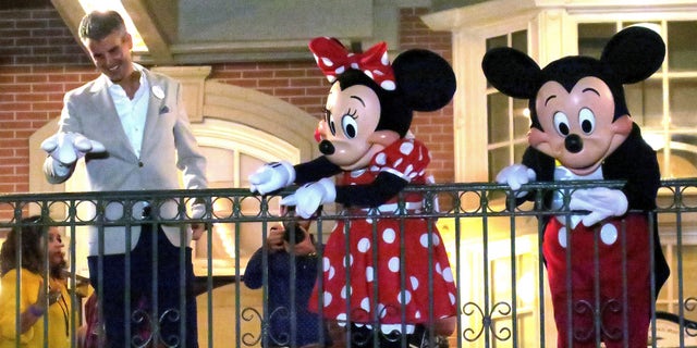 With Minnie and Mickey Mouse, Walt Disney World President Josh D'Amaro waves to guests gathered on Main Street USA, in the Magic Kingdom in the final minutes before the park closed on March 15. (Joe Burbank/Orlando Sentinel)/Orlando Sentinel via AP)