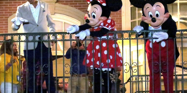 With Minnie and Mickey Mouse, Walt Disney World President Josh D'Amaro waves to guests gathered on Main Street USA, in the Magic Kingdom in the final minutes before the park closed on March 15. (Joe Burbank/Orlando Sentinel)/Orlando Sentinel via AP)