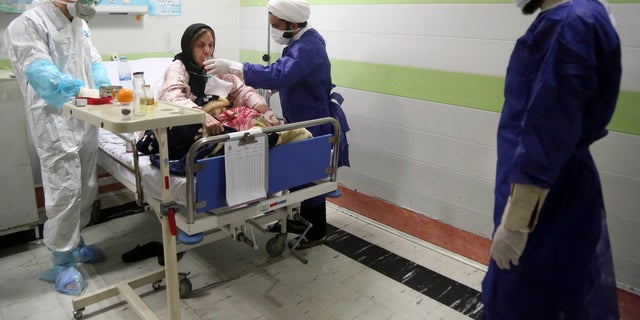 FILE — In this Saturday, March 7, 2020 file photo, a cleric, right, assists a medic treating a patient infected with the new coronavirus, at a hospital in Qom, about 80 miles (125 kilometers) south of the capital Tehran, Iran. (Mohammad Ali Marizad/Rasa News Agency via AP, File)