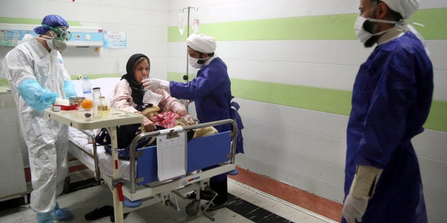 FILE — In this Saturday, March 7, 2020 file photo, a cleric, right, assists a medic treating a patient infected with the new coronavirus, at a hospital in Qom, about 80 miles (125 kilometers) south of the capital Tehran, Iran. (Mohammad Ali Marizad/Rasa News Agency via AP, File)