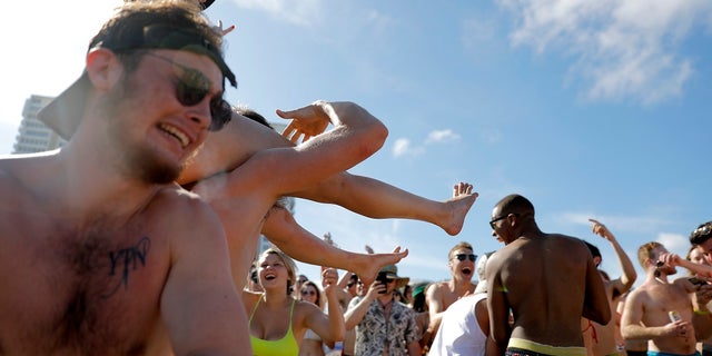 Spring break revelers party on the beach on Tuesday in Pompano Beach, Fla. As a response to the coronavirus pandemic, Florida Gov. Ron DeSantis ordered all bars be shut down for 30 days beginning at 5 p.m. and many Florida beaches are turning away spring break crowds urging them to engage in social distancing. (AP Photo/Julio Cortez)