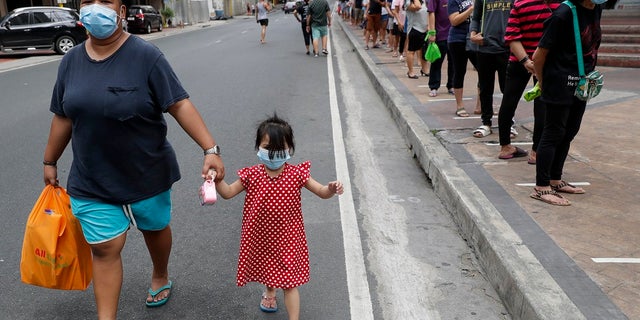 Residents line outside a supermarket in Manila, Philippines, while the government implements a localized quarantine as a precautionary measure against the spread of the new coronavirus. (AP Photo/Aaron Favila)