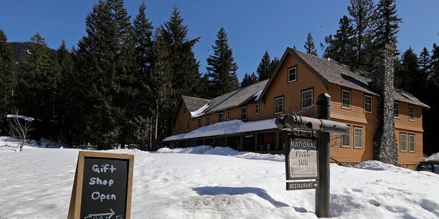 A sign at the National Park Inn at Longmire offers food orders to-go from the inn's restaurant at Mount Rainier National Park, Wednesday, March 18, 2020, in Washington state. Most national parks are remaining open during the outbreak of the new coronavirus, but many are closing visitor centers, shuttles, lodges and restaurants in hopes of containing its spread. (AP Photo/Ted S. Warren)