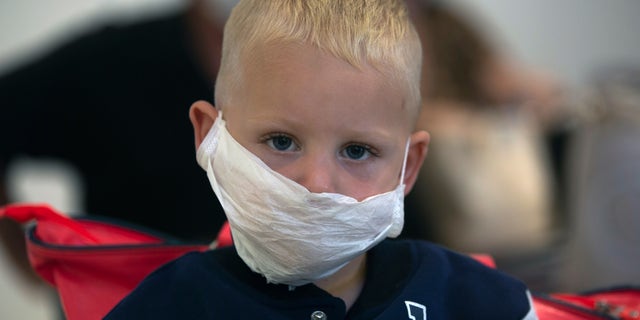 A boy wears a mask as he waits to travel from O.R.Tambo Airport in Johannesburg, South Africa, Thursday, March 19, 2020. As more African countries closed their borders, the coronavirus' local spread threatened to turn the continent of 1.3 billion people into an alarming new front for the pandemic. (AP Photo/Denis Farrell)